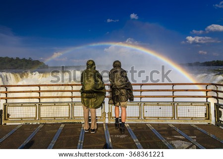 Travelers at Iguazu Falls. View of the rainbow and a waterfall. Argentina.