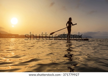 Silhouette of a beautiful woman on Stand Up Paddle Board. SUP.