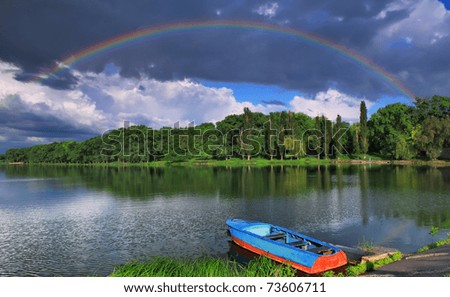 Rainbow over the lake with a boat on a summer evening