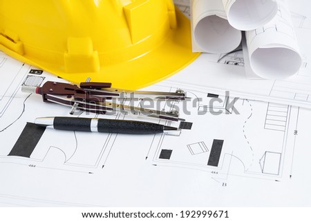 Engineer workplace with blueprints, compass, pen and safety helmet
