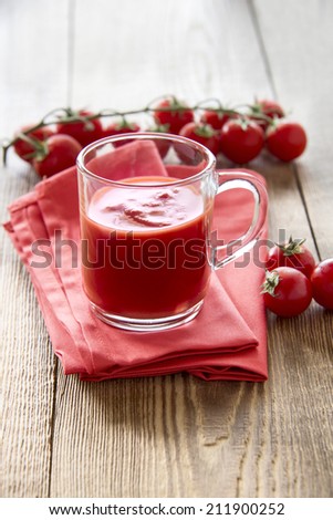 Tomato juice with cherry tomatoes on wooden table