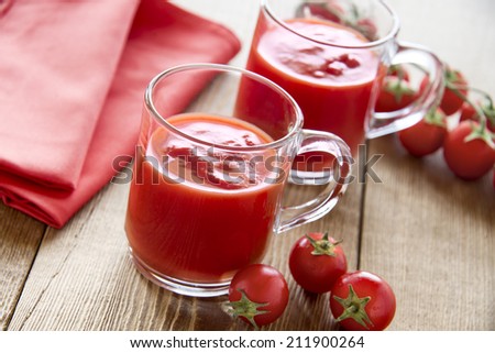 Tomato juice glasses with cherry tomatoes on wooden table