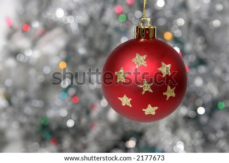 Red christmas ball with stars against cold background with flickering lights