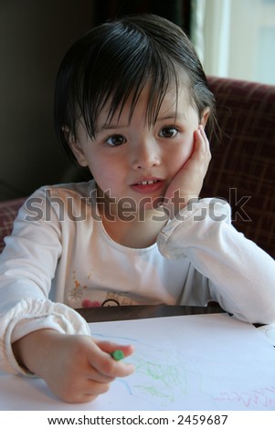 Child that is making a drawing, pauses and looks with curious eyes