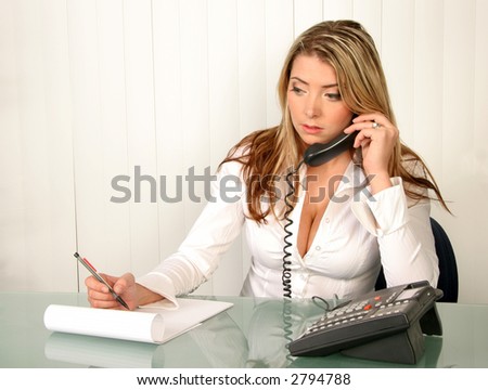 Young beautiful business woman in office holding phone and taking notes