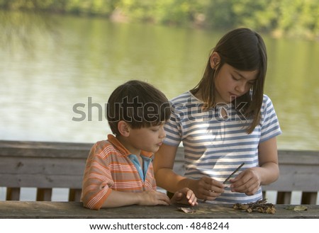 Young girl and boy studying nature at the lakeside
