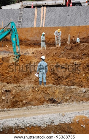 Construction workers on a construction site with excavating equipment in Japan