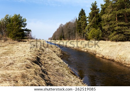 a small village shallow river in the fall. On the banks of the river is a forest.