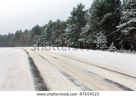 Snow-covered after a snowfall road about road turn (signs on abrupt turn are visible)