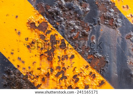 Rusted steel metal on yellow black strip pattern with water drip, and faded erosion