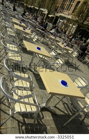 Chairs and tables in outdoor restaurant on cobbled square of old town