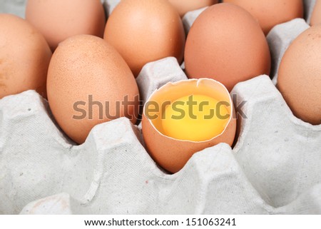 brown eggs in carton with broken egg