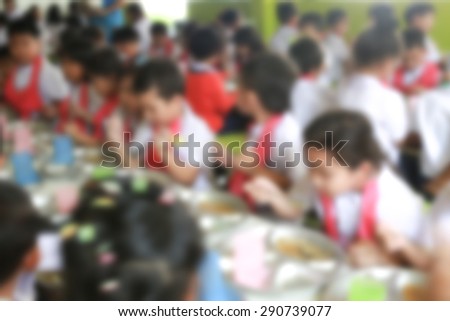 blurred students sitting at cafeteria table eating lunch