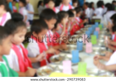 blurred students sitting at cafeteria table eating lunch