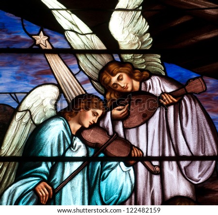 Detail of Christmas stained glass window depicting two angels playing musical instruments Detail of Christmas stained glass window depicting two angels playing musical instruments