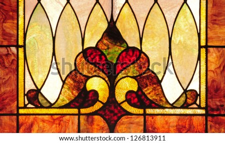 Detail of stained glass window with stylized fleur-de-lis flower and oval designs