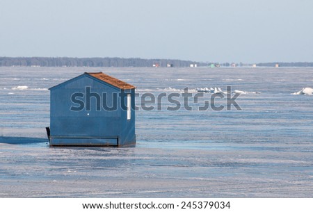 Winter scene: blue ice fishing house on frozen lake