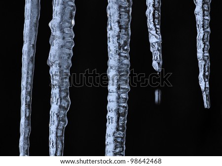 closeup of Icicles hanging from eaves, one of them dripping as it melts