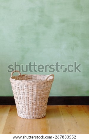 empty woven basket in front of green cement wall