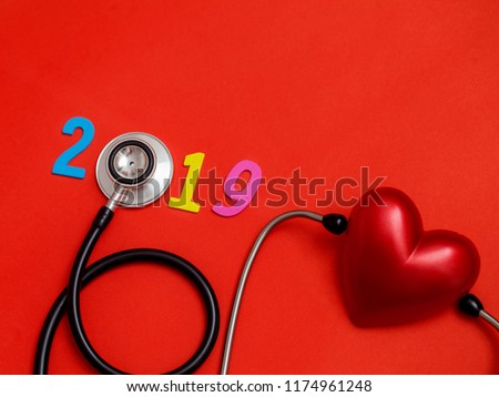 Wooden colorful on text 2019 banner for health care and Red heart love medical concept. black stethoscope,on table red background.