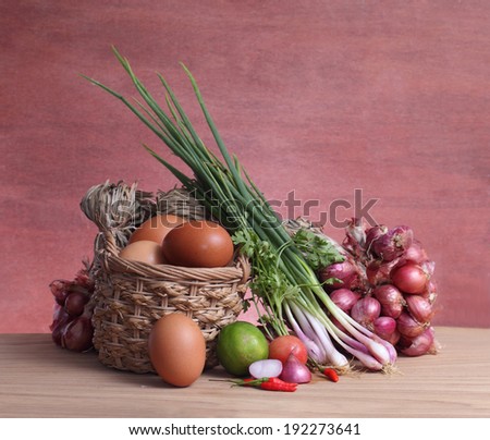 Thai vegetables,eggs in basket with onions on wood table.