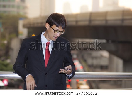 Man on smart phone - young business man. Casual urban professional businessman using smartphone smiling happy outside office building. Handsome man wearing suit outdoors.