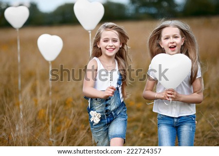 portrait of a little girls in a field with white balloons
