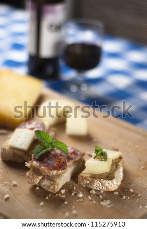 A traditional blue table with a plate with cheese and salami tapas and wine from Portugal