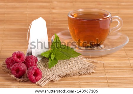 Fruit tea(tea package) in cup with raspberry