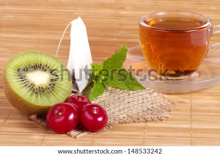 Tasty tea (tea package) in cup with fruits