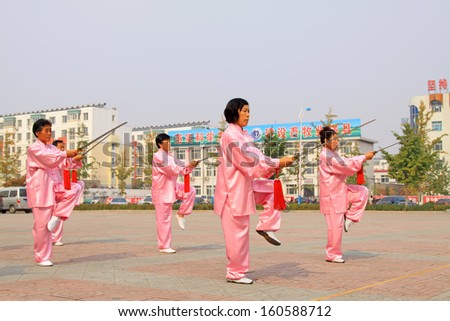 LUANNAN COUNTY - October 20: A group of old people is performing Tai chi chuan on the gym in the square, on October 20, 2011, LuanNan county, hebei province, China