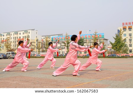 LUANNAN COUNTY - OCTOBER 20: A group of old people is performing Taiji sword on the gym in the square, on October 20, 2011, LuanNan county, hebei province, China