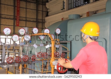 LUANNAN COUNTY - AUGUST 26: A worker was control valve in a transformer room of a factory, On August 26, 2011, luannan county, hebei province, china.