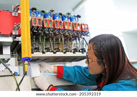 TANGSHAN CITY - MAY 28: Women worker are maintenance ink-jet printing machine nozzle, on may 28, 2014, Tangshan city, Hebei Province, China