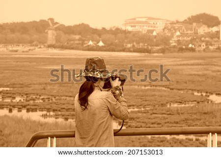 QINHUANGDAO CITY- JUNE 1: A female photographer was photographing in a wetland park, June 1, 2014, Qinghuangdao city, Hebei Province, China