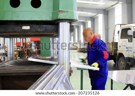 TANGSHAN CITY - MAY 29: Workers operating hydraulic press processing products in a factory, on may 29, 2014, Tangshan city, Hebei Province, China