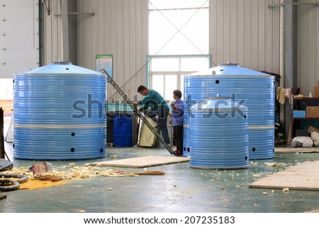 TANGSHAN CITY - MAY 29: Workers making solar water heater in a production workshop, on may 29, 2014, Tangshan city, Hebei Province, China
