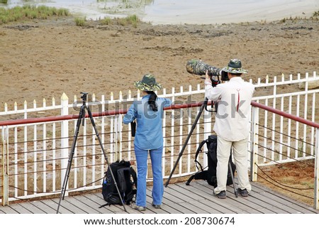 QINHUANGDAO CITY- JUNE 1: A man and a woman two photographers were photographing in a wetland park, June 1, 2014, Qinghuangdao city, Hebei Province, China