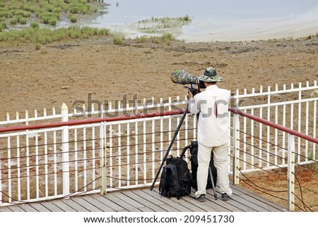 QINHUANGDAO CITY- JUNE 1: Male photographer was photographing in a wetland park, June 1, 2014, Qinghuangdao city, Hebei Province, China