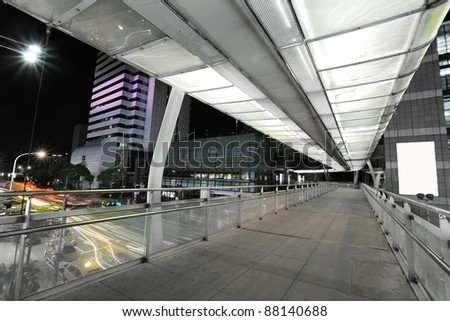 modern skybridge with a big sing board on the right side and car trails on the left