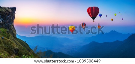 Colorful hot air balloons flying over mountain with sunrise at at phucheefa mountain. Chiang Rai Province, Thailand