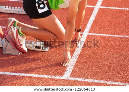 Woman ready to start running on running track.