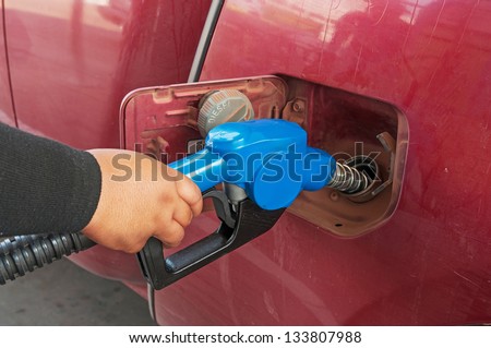 Male hand refilling the car with fuel in to the tank