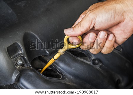 Hand checking lubricant level of car