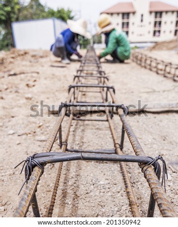 Asian women construction worker installing binding steel wires to reinforcement steel bars in construction site.