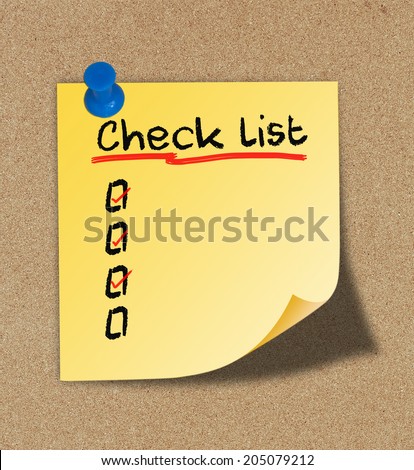 Text check list on yellow note pinned on cork board.