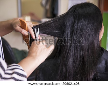 Hands with a comb cutting hair of woman