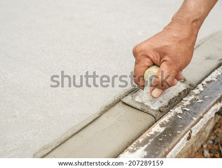 Workers hand using trowel with wet concrete, Construction road with cement. Selective focus.