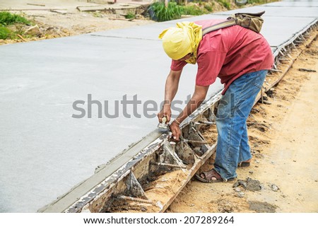 Worker using trowel with wet concrete, Construction road with cement. Selective focus.