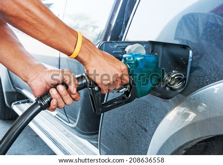 Man pumping gasoline fuel in car at gas station
